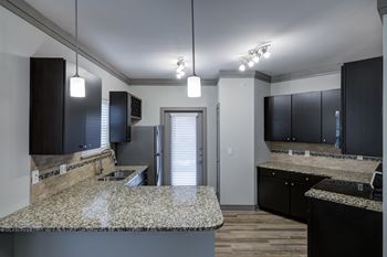 Kitchen with dark cabinetry and granite island